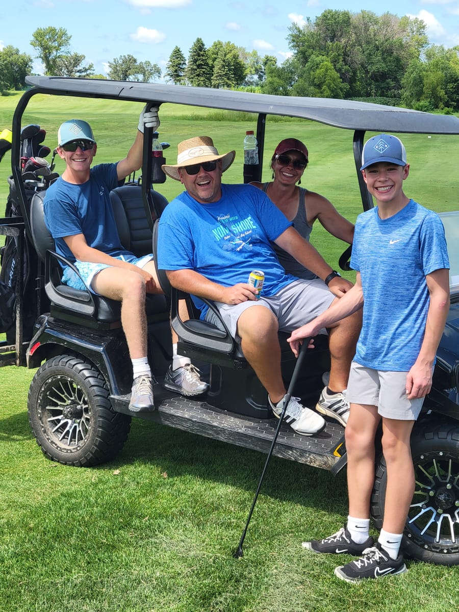 Family riding together in a golf cart, smiling